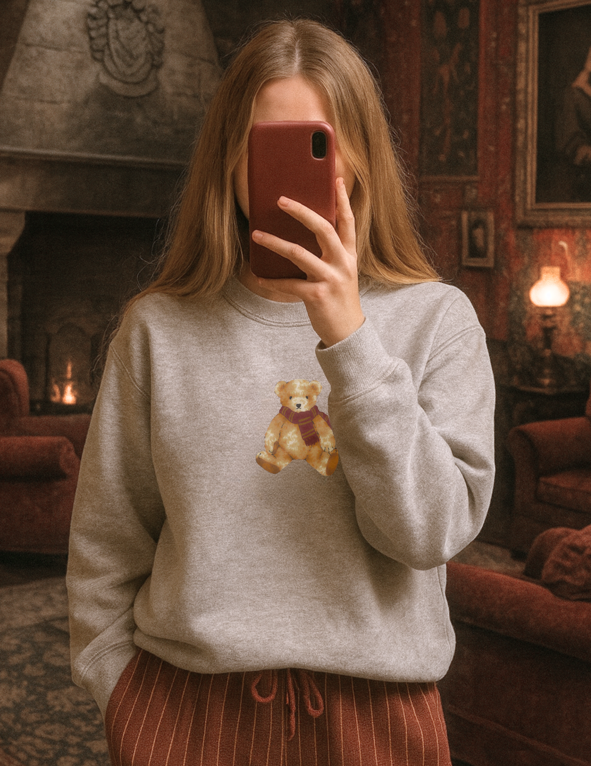 Person wearing a gray sweatshirt with a teddy bear design in a cozy room.